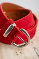 Cinto de gamuza color rojo con hebilla metálica plateada.