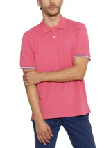 Chomba de piqué color rosa con cuello clásico y tapeta de dos botones. Tiene mangas cortas con puños acanalados con detalles de líneas blancas y azules. Presenta un logo bordado en el pecho.