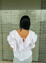Blusa blanca con escote en V, mangas cortas con volados y lazos en el escote.
