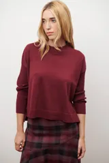 Buzo de punto color bordó, con cuello redondo, manga larga y corte holgado.