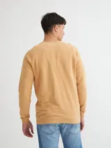 Buzo color tostado con cuello redondo, corte central y mangas raglán. Presenta un estampado frontal con la palabra "UNFRMDENIM" en negro.