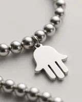 Pulsera de acero quirúrgico compuesta por pequeñas cuentas esféricas y un dije colgante en forma de mano de Fátima (Hamsa).