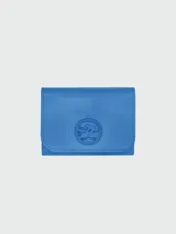 Billetera de cuero azul con solapa y logo de la marca grabado en relieve en el centro.