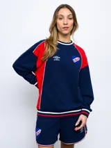 Buzo de felpa azul marino con mangas raglán rojas y detalles tricolor en puños, mangas y cuello. Incluye logo de Umbro bordado en el pecho y escudo del Club Nacional de Football.