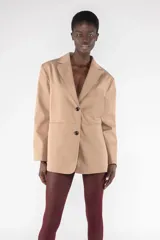 Blazer color beige de corte holgado con solapas y cierre con dos botones.