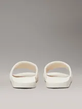 Ojotas Calvin Klein con tira ancha de tejido jacquard que presenta el logo de la marca en relieve. Poseen plantilla ergonómica moldeada con soporte para el arco y suela de EVA.