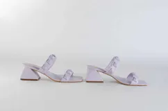 Sandalias rojas de tacón con dos tiras sobre el empeine adornadas con tachas piramidales. El tacón es ancho y de altura media.