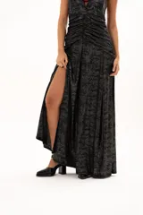 Vestido largo de fiesta con escote halter profundo y espalda descubierta. Presenta un diseño drapeado en la zona central del torso y una falda fluida con tajo lateral. Confeccionado en tejido con acabado brillante tipo lurex.