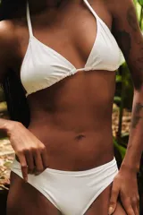 Conjunto de bikini blanco compuesto por un corpiño triangular con tiras para atar al cuello y a la espalda, y una bombacha clásica de tiro medio.