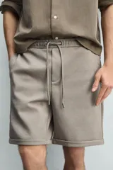 Bermuda regular fit de tejido elástico color blanco, con cintura elástica ajustable mediante cordón, bolsillos delanteros y bolsillos traseros de vivo.