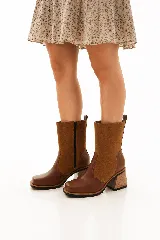 Bota de caña media combinada en cuero liso y descarne color marrón, con punta cuadrada, cierre lateral y taco ancho de madera.