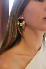Aros de bronce con diseño circular abierto y tres pequeñas piezas circulares texturadas colgando en la parte inferior.