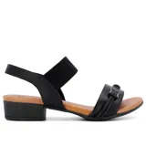 Sandalia de cuero negra con elástico en el tobillo, taco bajo y hebilla decorativa.