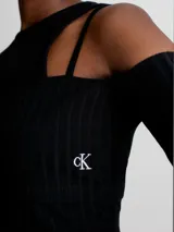 Remera Calvin Klein negra de punto canalé con doble capa y efecto 2 en 1. Tiene mangas largas con hombros descubiertos y logo bordado en el lateral. Corte slim cropped.