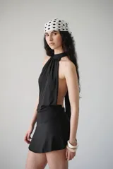 Vestido corto marrón con cuello alto tipo halter que se ata por detrás, diseño sin mangas, espalda descubierta, faja en la cintura y falda ajustada.