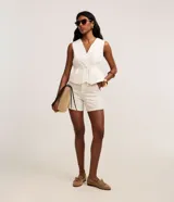 Short de cintura alta en tejido de sarga color beige, con diseño de rayas verticales finas, trabillas para cinto y estilo sastre.