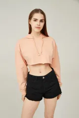 Buzo corto color durazno con capucha y cordones ajustables, de manga larga y corte holgado.