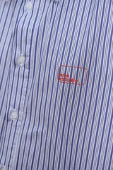 Camisa de corte oversize con estampado a rayas verticales en tonos azul y blanco, cuello clásico y cierre frontal con botones.