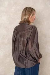 Camisa de organza blanca con cuello mao, diseño de manga larga tipo murciélago y cierre frontal con botones. Presenta un corte holgado y fluido.