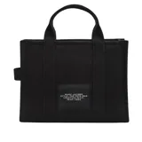 Bolso tote de lona color negro con estampado frontal en blanco que reza 'THE TOTE BAG MARC JACOBS'. Cuenta con doble asa superior, cierre de cremallera y correa larga ajustable y extraíble.