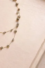 Collar largo de cadena fina dorada con pequeñas piedras naturales engarzadas a lo largo de toda la pieza.