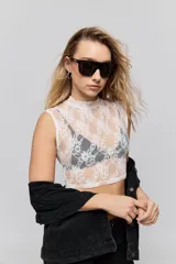 Top de encaje blanco con cuello alto y diseño sin mangas, de corte ajustado.