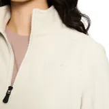 Buzo polar de micropolar ligero, color beige, con cuello alto y cierre frontal parcial de un cuarto de cremallera. Presenta ribetes elásticos en el cuello, puños y dobladillo.