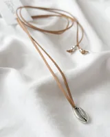 Gargantilla tipo choker con cordón fino color beige y dije plateado en forma de concha.