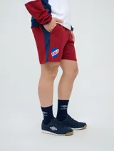 Bermuda deportiva Umbro del Club Nacional de Football, color azul marino, con cordón ajustable en la cintura, bolsillos laterales, el escudo del club en una pierna y el logo de la marca en la otra.