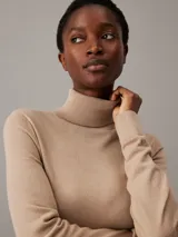 Vestido color beige de lana merino, corte recto, largo hasta la rodilla, cuello alto y mangas largas.