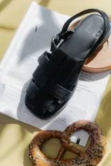 Sandalias de cuero marrón con diseño de tiras entretejidas y hebilla lateral.