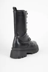 Borcego negro de caña media en símil cuero, con interior acolchonado, cordones a tono, cierre en uno de sus laterales y plataforma tipo tractor de 6cm de alto.