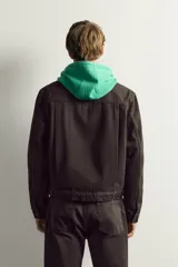 Cazadora cropped fit marrón de denim de algodón, con cuello solapa, manga larga con puño abotonado, bolsillo de parche en el pecho, pliegues verticales en el delantero y cierre frontal con botones.