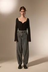 Pantalon de jean estilo barrel con lavado oscuro, tiro medio y detalle de tachas metálicas a lo largo de las costuras laterales.