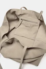 Bolso tipo maxi shopper confeccionado en serraje, con diseño minimalista y doble asa de hombro. Cuenta con un compartimento principal amplio y un bolsillo interior con cierre.