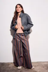 Pantalón de jean tiro medio, corte wide leg, confeccionado en tela de algodón con rayas verticales marrones y azules.