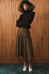 Falda midi de tiro medio con diseño asimétrico y acabados desflecados. Presenta un patrón de cuadros tipo príncipe de Gales en tonos tierra y cierre lateral con cremallera oculta.