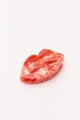 Broche para el pelo tipo clip con diseño de labios en color coral con efecto marmolado.