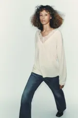 Jersey negro de manga larga con escote en V adornado con encaje negro.