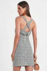 Vestido corto de tweed con estampado a cuadros en tonos gris, celeste y blanco. Tiene breteles anchos, escote cuadrado y corte ajustado.