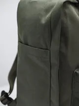 Mochila color verde militar con diseño clásico y minimalista. Cuenta con un compartimento principal con cierre de doble cremallera, un bolsillo frontal con cierre y dos asas superiores con broche. En el frente, tiene un parche circular con el texto "FORUM INDUSTRIES CO." en rojo.
