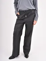 Pantalon de cuero sintetico color negro, de corte recto y holgado, con cintura elastizada y cordon de ajuste frontal.