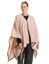 Ruana de tejido soft color beige, con escote en V, cierre frontal con botones metálicos y bordes ribeteados en cuero sintético negro.