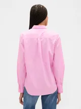 Camisa de manga larga color celeste, con cuello clásico, cierre frontal de botones, bolsillo en el pecho con detalle bordado y dobladillo redondeado.