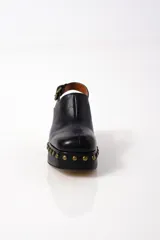 Zuecos negros de cuero con plataforma, tacón de bloque y tachuelas doradas.