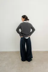 Pantalón de tiro medio-alto con piernas anchas y corte recto. Presenta cierre frontal con botón, bolsillos laterales y detalles de costuras verticales. Confeccionado en tencel.