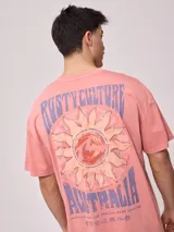 Remera de algodón con efecto lavado, color rosado, de calce oversize. Presenta un estampado grande en la espalda con un sol estilizado, el logo de Rusty y el texto "RUSTY CULTURE AUSTRALIA".