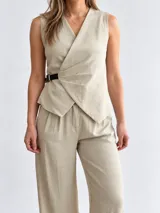 Conjunto de dos piezas para mujer en color beige, compuesto por un chaleco cruzado sin mangas con cinturón lateral y un pantalón de corte amplio.