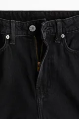 Jean de tiro alto con diseño de cinco bolsillos y perneras amplias de corte recto, confeccionado en denim negro rígido.
