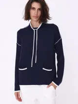 Sweater color crema con cuello alto, corte holgado y detalles en negro en cuello, puños, ruedo y bolsillos frontales.